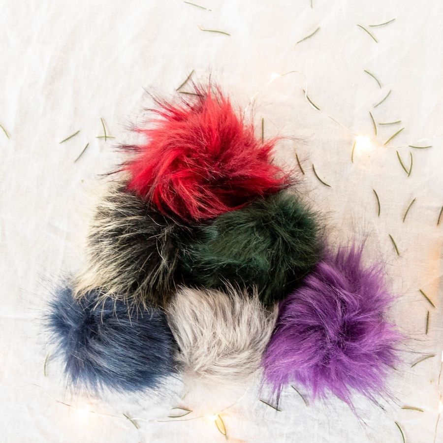 red, green, black and gray, purple, blue and gray pom poms in a triangle