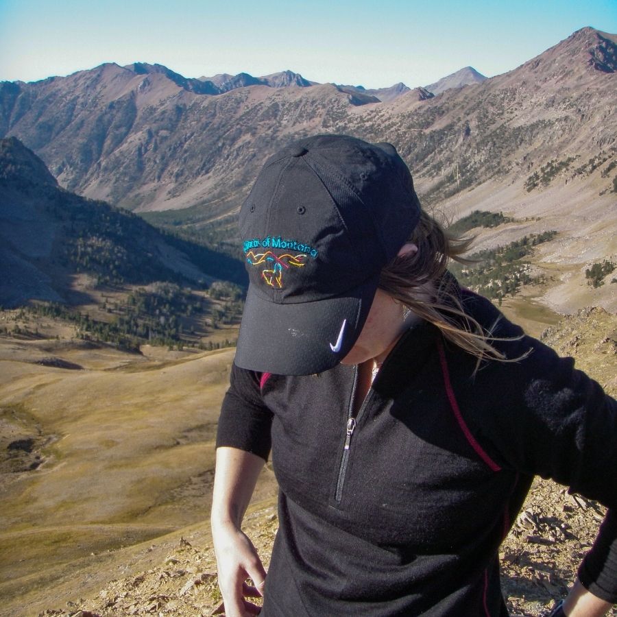 woman in the mountains wearing black nike alpacas of montana baseball cap