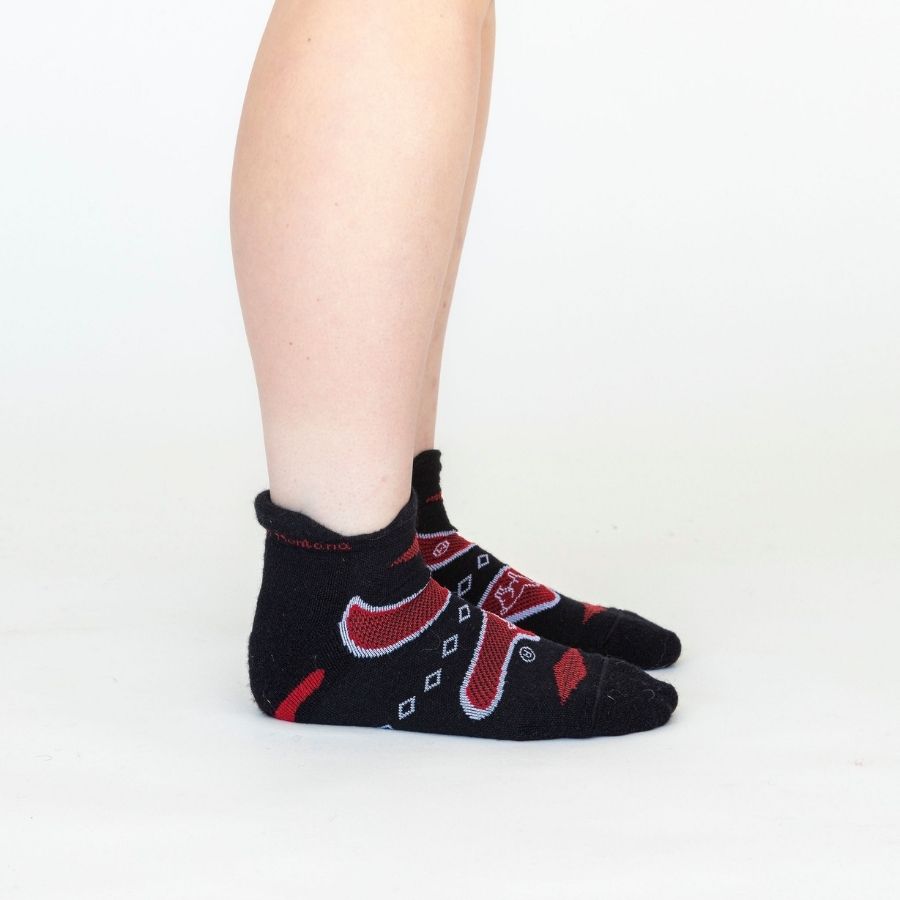 person&#39;s lower legs wearing red and black alpaca wool endurance socks against white background