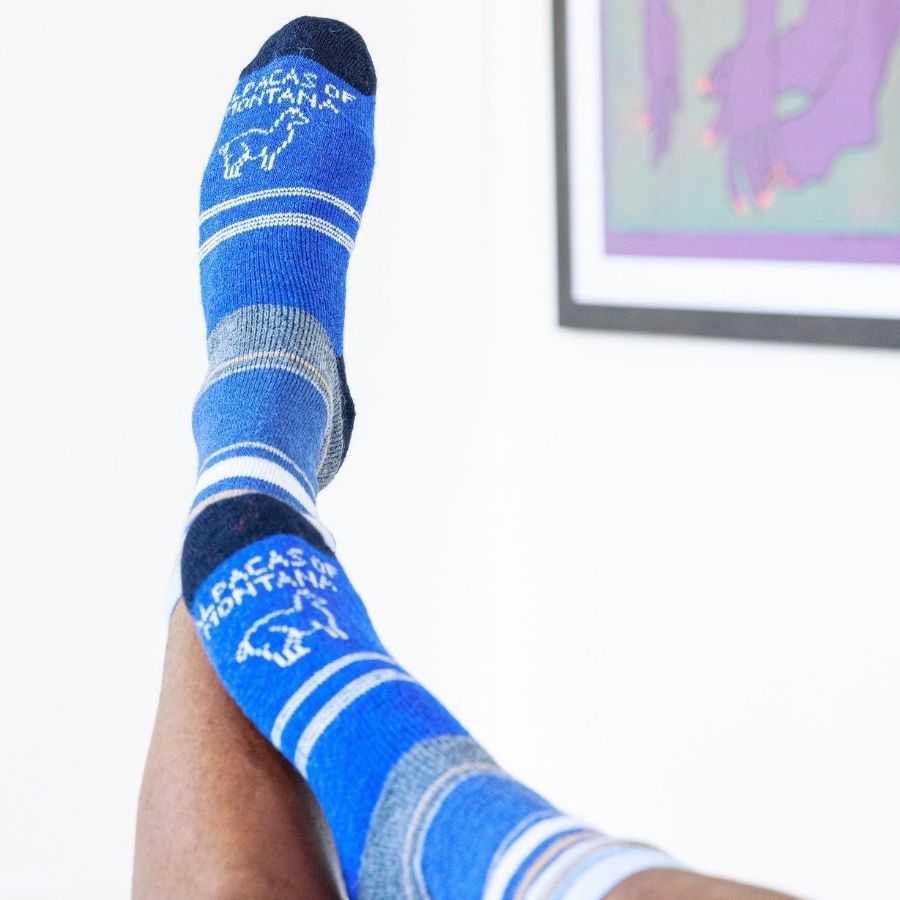 person&#39;s feet in the air wearing blue tan and white alpaca wool urbanite socks
