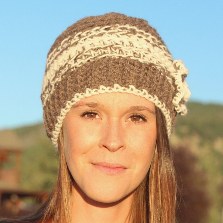 brown and white hand knit alpaca beanie hat with flower on smiling woman