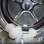 five white alpaca wool dryer balls in a stainless steel dryer