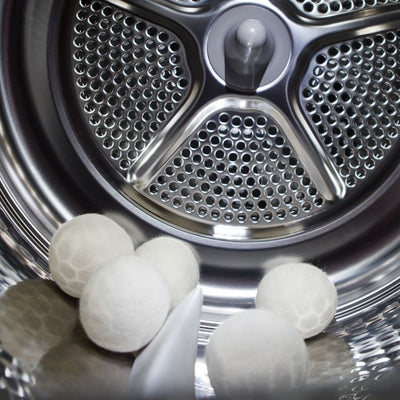 five white alpaca wool dryer balls in a stainless steel dryer