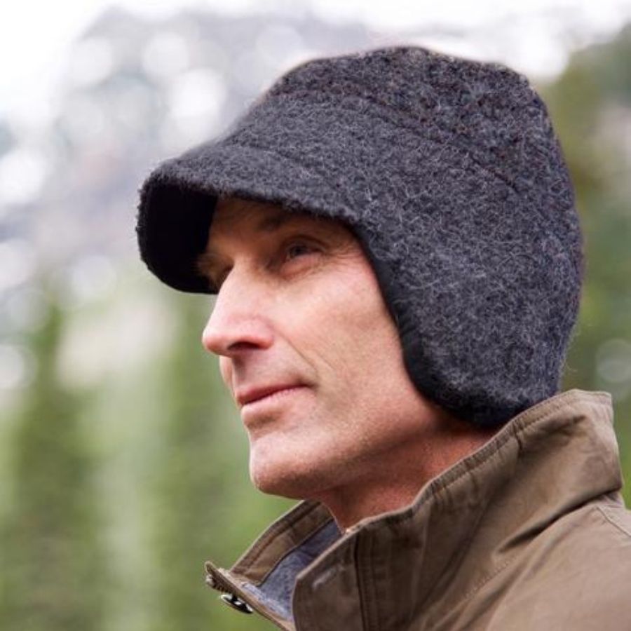 A close up photo of a man wearing a brown coat and a dark gray Alpacas of Montana an extremely warm cozy soft windproof comfortable moisture wicking thermal alpaca fleece wool windstopper winter hat for hiking, skiing, hunting, fishing, outdoors.