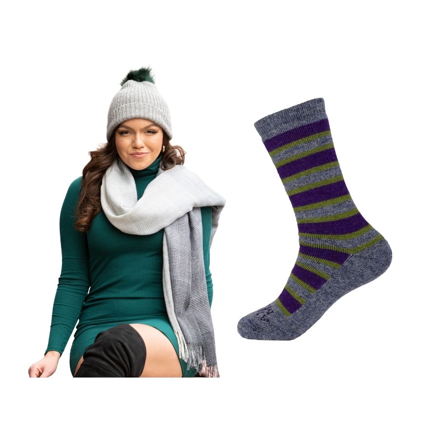 woman sitting with her legs crossed wearing a green dress and shades of gray alpaca wool shawl and green, gray and purple alpaca wool urbanite socks