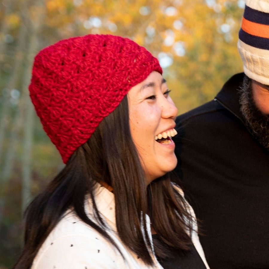woman smiling wearing red hand knit alpaca wool scallop hat