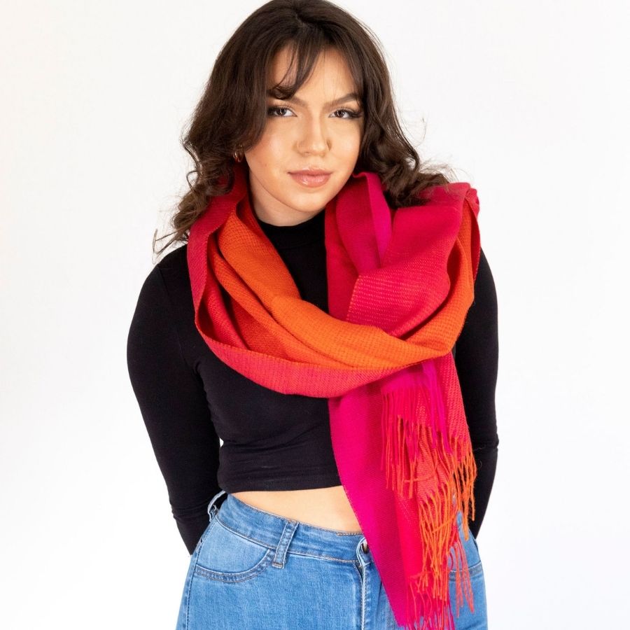 woman standing with her arms behind her back wearing red ruckus alpaca wool shawl