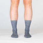 Front view of a person's lower legs against a white background wearing medium light gray Alpacas of Montana professional soft comfortable moisture wicking business casual alpaca wool dress socks for men and women.