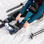 person sitting in snow wearing black and blue alpaca wool ski socks