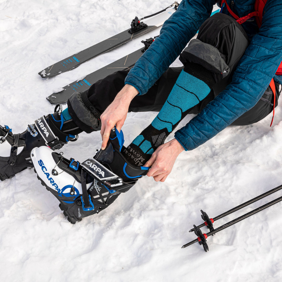 person sitting in snow wearing black and blue alpaca wool ski socks