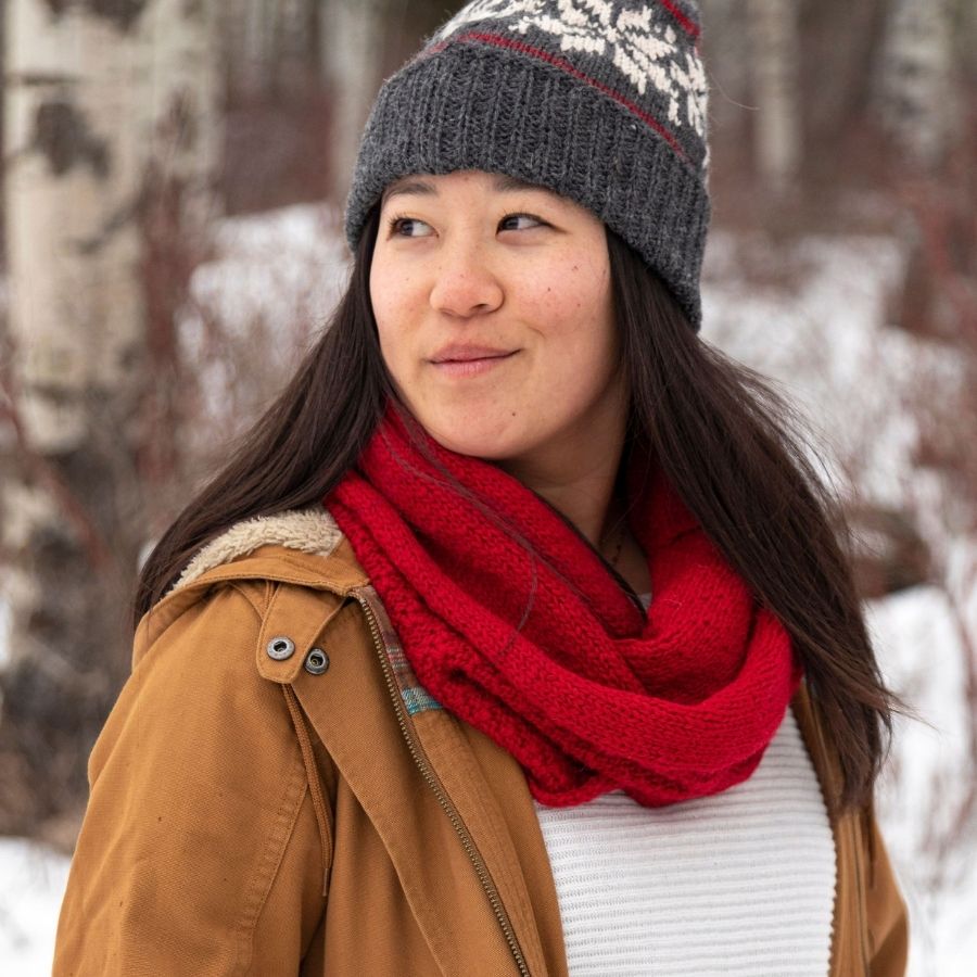 woman smiling into the distance wearing handmade red alpaca wool infinity scarf