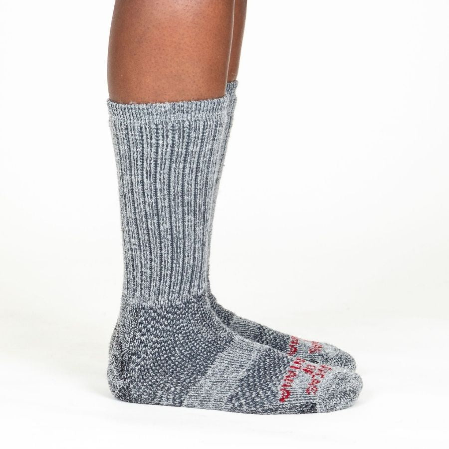 A side view of a person's lower legs wearing Alpacas of Montana cozy soft warm comfortable thermal moisture wicking everyday winter fishing hiking snowshoeing hunting outdoors silver gray extra cushion boot socks.
