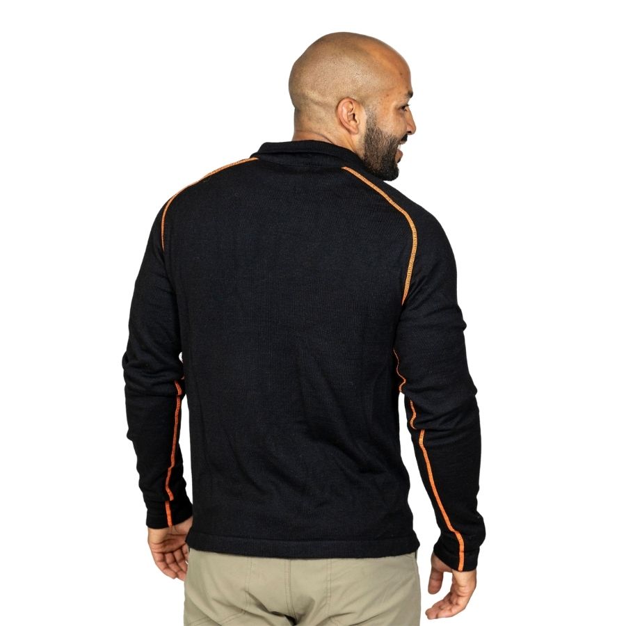 A smiling bald man with a black beard standing facing away from the camera in front of a white background. He is wearing khaki pants and a black with orange stitching Alpacas of Montana warm thermal soft cozy comfortable activewear outerwear athletic moisture wicking antimicrobial men's fashion stylish luxury mid-layer quarter-zip alpaca wool long sleeve pullover top for outdoors camping climbing hiking skiing hunting fishing running winter.